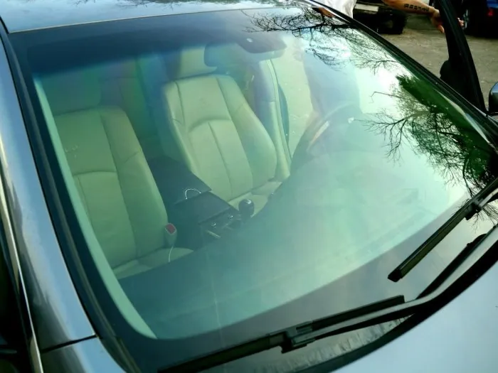 The windshield, covered with heat-reflective / thermal film, has a greenish or bluish tint